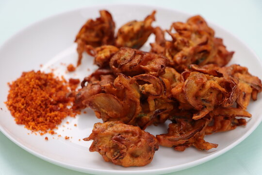 Crispy kanda pakora, kanda bhaji or onion fritters. A road side snack served with red garlic chutney. favourite monsoon snack in India.  