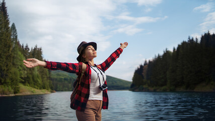 Young woman standing by lake on a walk outdoors in summer nature, relaxing. © Halfpoint