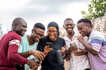 group of young africans using their phones, hanging out together, students leisure on campus, viewing content on a phone together, laughing