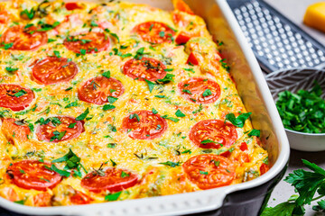Fototapeta na wymiar Baked omelet (frittata) with tomatoes and cheese in oven dish, Top View. Baked omelet with vegetables and cheese.