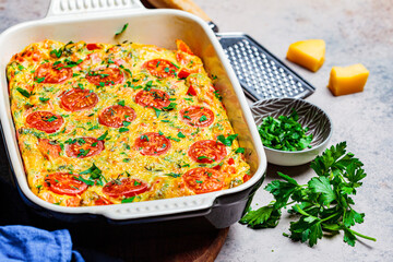 Baked omelet (frittata) with tomatoes and cheese in oven dish, Top View. Baked omelet with vegetables and cheese.