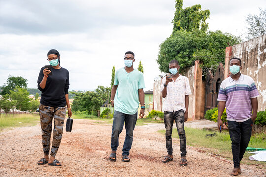 A Group Of Young Black People Strolling In The Park, Wearing Face Masks, Walking Apart From Each Other