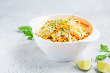Fresh coleslaw salad with cabbage and carrots in white bowl.