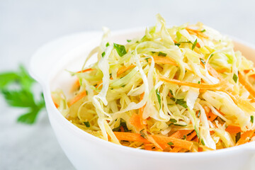 Fresh coleslaw salad with cabbage and carrots in white bowl.