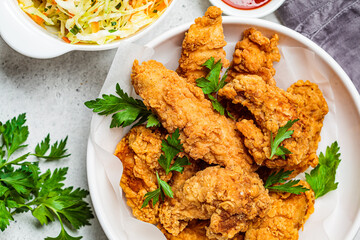 Crispy fried chicken in a white bowl with cole slaw salad and sauce.