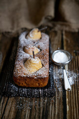 Chocolate cake with pears and chocolate with icing sugar on a wooden table