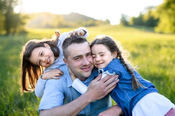 Father with two small daughters having fun outdoors in spring nature, hugging.