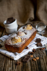 Chocolate cake with pears and chocolate with icing sugar on a wooden table