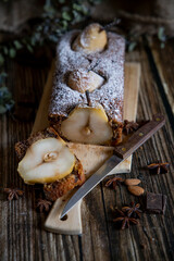 Chocolate cake with pears and chocolate with icing sugar on a wooden table