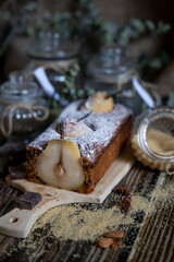 Chocolate cake with pears and chocolate with icing sugar on a wooden table