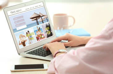 Woman using laptop to plan trip, closeup. Travel agency website