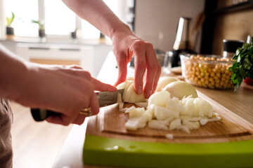 Woman hands, cutting onions, dill while preparing ingredients for falafel. Healthy diet