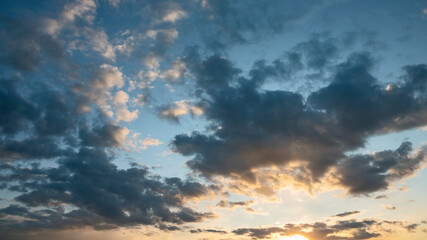 sun sets behind the clouds in the blue evening sky as a natural background