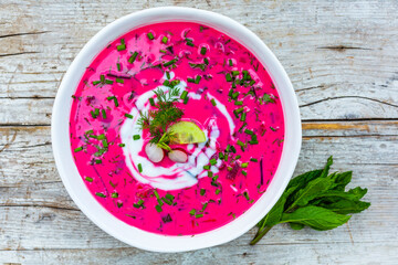 Cold beetroot soup with fresh seasonal vegetables on wooden background. 