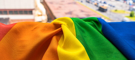 The LGBT community symbol gay pride rainbow hangs on a window overlooking the street. 