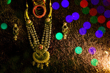 gold jewellery golden necklace(haar) bracelets butti dark background with bokeh bride getting ready for beauty parlour beautiful ornaments