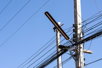 Old Street light on concrete pole with tangle of electrical cables.