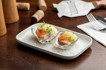 Oysters garnished with red caviar on salt and plate