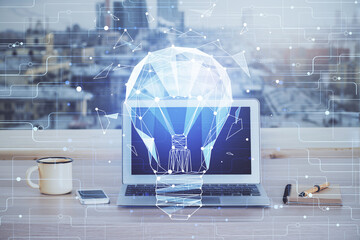 Computer on desktop in office with bulb icon hologram. Multi exposure. Concept of idea.