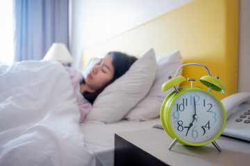 The girl is sleeping in the morning There is an alarm clock at 7:00 am He is about to wake up to...