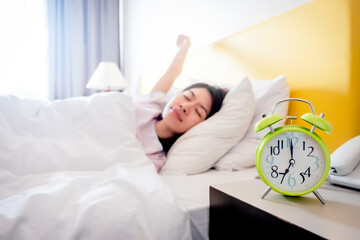 The girl is sleeping in the morning There is an alarm clock at 7:00 am He is about to wake up to...