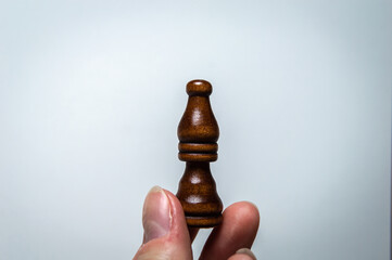 The hand holds a chess piece. Chess Bishop on a white background