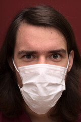 Caucasian young man in his late teens wearing a white facemask