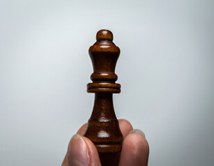 The hand holds a chess piece. Chess Queen on a white background