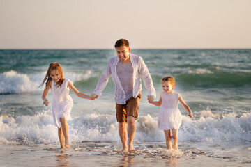 wet dad and daughters swimming in sea in clothes, playing and having fun.