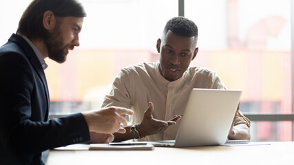 Horizontal image multi-ethnic businessmen looking at laptop screen discussing sales stats using new application business program, express opinion sharing thoughts working together on project concept