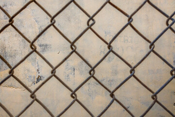 Close-up old iron wire fence vintage net on the background of concrete beige painted wall