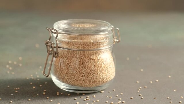 White raw quinoa, South American grain, female hands close glass jar. Healthy and gluten free food.