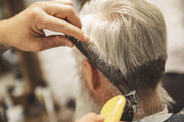 Hairdresser making stylish haircut for old man