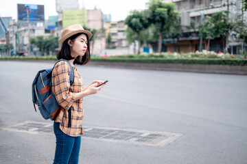 Asian female tourist Stand calling a taxi with an application on smartphone. Is a technology that...
