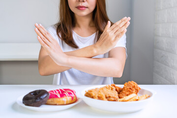 Young Aisan woman in white T-shirt doing hands signal in cross to deny junk food. reject unhealthy food concept. Close up