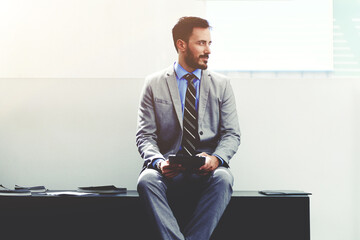 Handsome male manager in suit speaking on cell telephone during work break