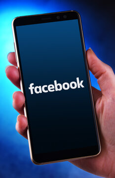 Hand holding smartphone displaying logo of Facebook