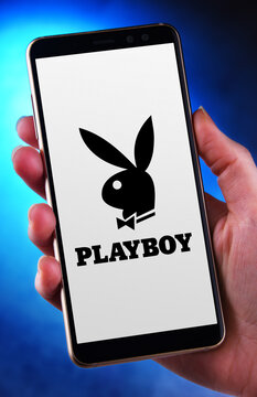 Hands holding smartphone displaying logo of Playboy