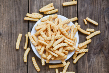 prawn crackers stick on white plate and wooden table background , homemade crunchy prawn crackers or shrimp crisp traditional snack