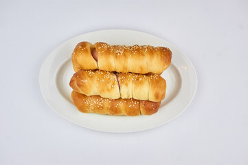 sausage in dough sprinkled with sesame seeds on a white background