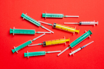 Top view of medical syringes with needles at red background with copy space. Injection treatment concept