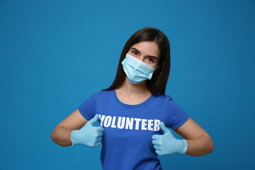 Female volunteer in mask and gloves on blue background. Protective measures during coronavirus...