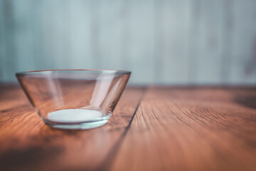 A measure of 1 TBSP of SALT in a transparent glass bowl on a brown wooden table with bright wooden background. Free space for your decoration/text.