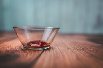 A measure of 1 TBSP of Tomato Ketchup powder in a transparent glass bowl on a brown wooden table with bright wooden background. Free space for your decoration/text.