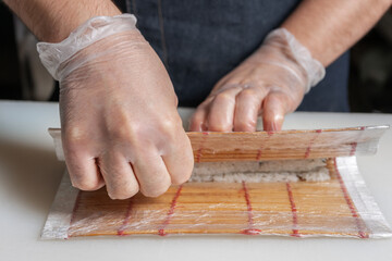 Sushi chef rolls the roll using a Mat