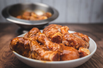 Close-up of a bowl full of marinated FRESH RAW ORGANIC CHICKEN DRUMSTICK with lots of spices on a dark brown wooden table.