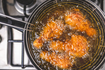 Frying Chicken in a pan full of oil. A pan with a frying basket. Concept of preparing Fried ORGANIC CHICKEN DRUMSTICK on the gas stove.