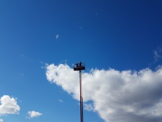 Fototapeta na wymiar people at the top of a cherry picker or tower and blue sky with cloud