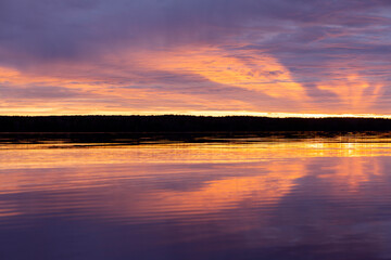 Water surface. Sunset sky background. Gold sunset sky with evening sky clouds over the lake. Small waves. Water reflection