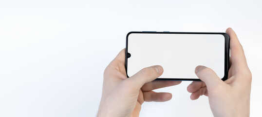 Obraz premium Male hands holding smartphone with blank screen horizontally on white background